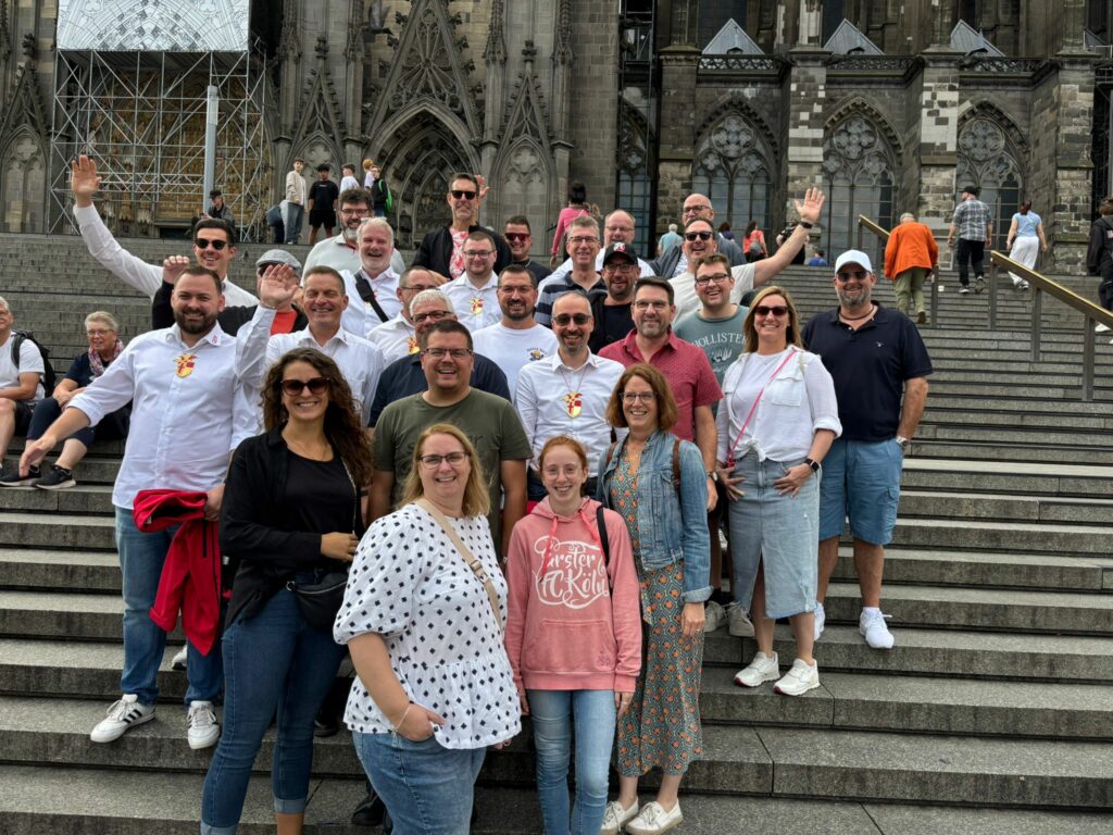Eine große Karnevalsgruppe posiert gut gelaunt am Kölner Dom
