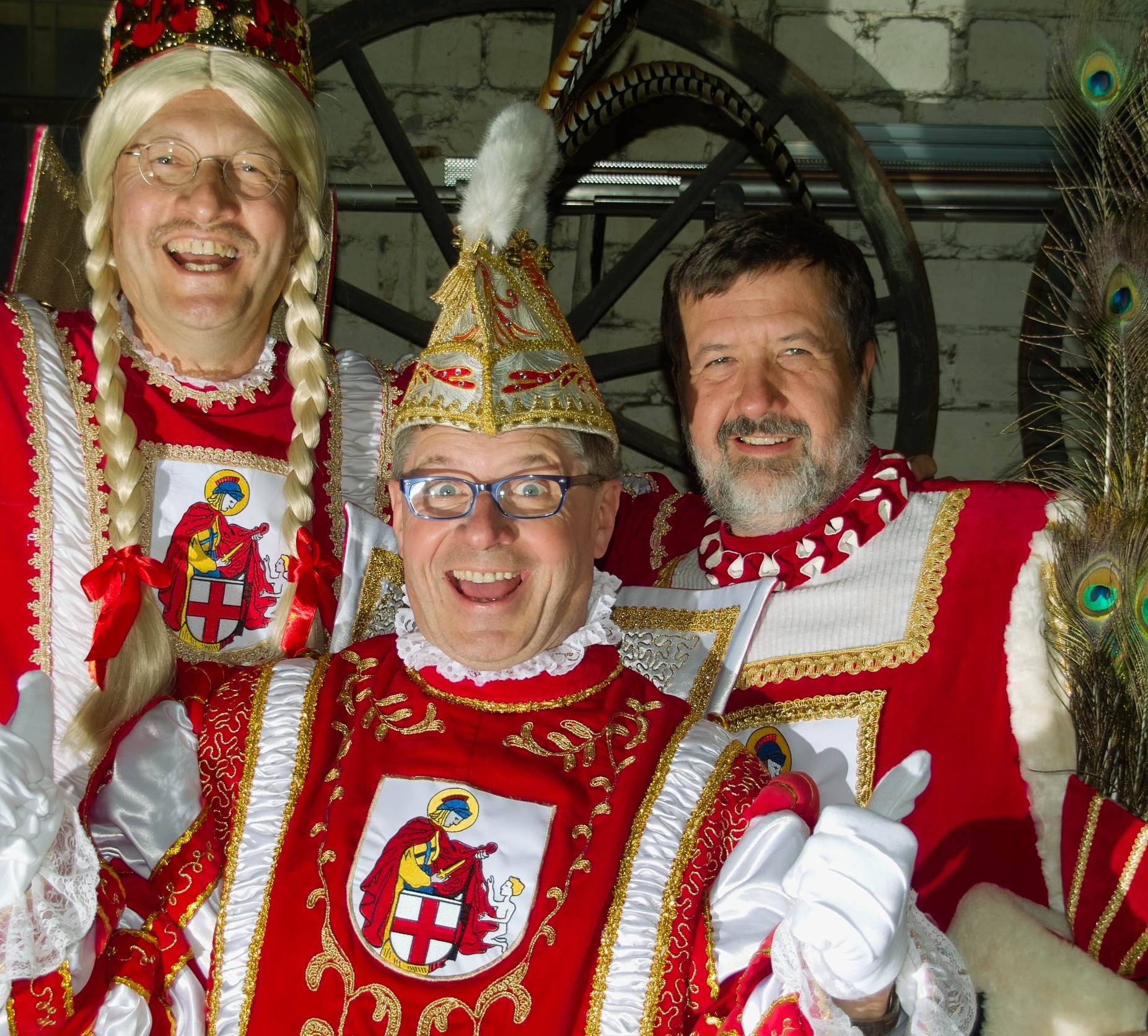 Drei Männer in traditionellen Karnevalskostümen, die fröhlich in die Kamera lachen.